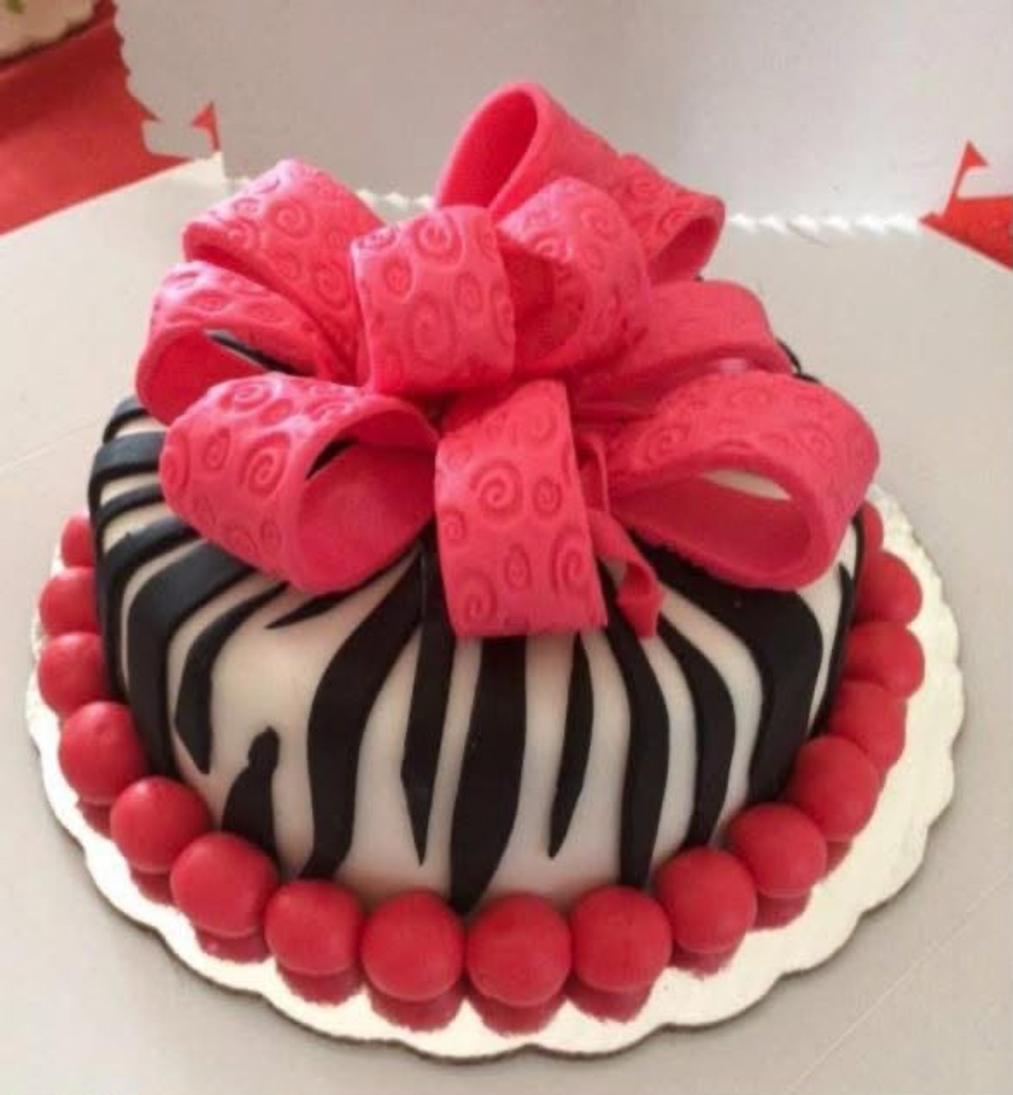 Queque decorado con patrón de zebra, lazo rosado y detalles rojos